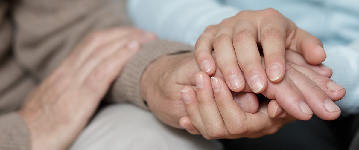 Caregiver holding hands of an elder