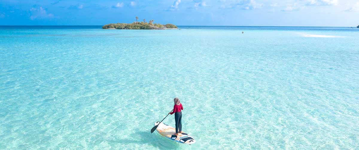 Person paddle-boarding on shallow ocean
