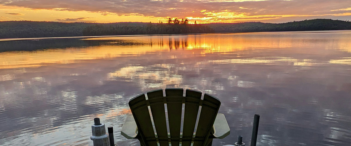 A calm lake with a sunset in the background