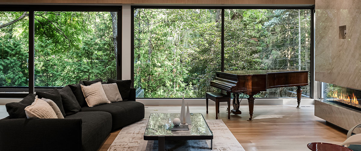 Interior of a home with sofa, large windows and a grand piano.